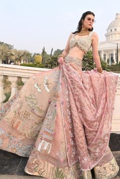 a woman in a pink lehenga standing on steps with her hands on her hips