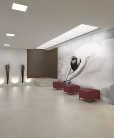 an empty lobby with two red benches and a large painting on the wall behind it