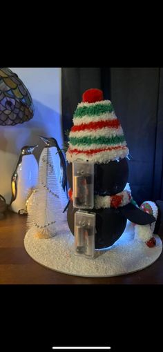 a penguin with a christmas hat on top of it's head sitting in front of a lamp