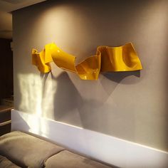 a yellow sculpture on the wall next to a couch