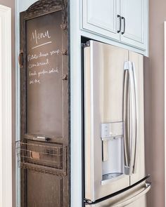 a refrigerator freezer sitting inside of a kitchen next to a chalkboard menu on the door