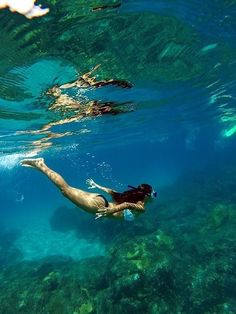 a woman is swimming in the water with her feet above the water's surface