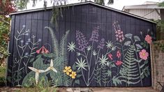 a black building with flowers painted on it's side and trees in the background