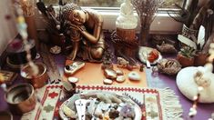 an assortment of items on a table in front of a window with candles and figurines