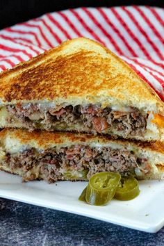 a sandwich cut in half sitting on top of a white plate next to a pickle