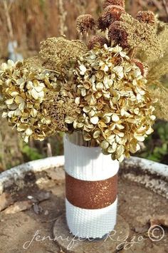 a vase filled with lots of flowers sitting on top of a tree stump