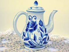 a blue and white tea pot sitting on top of a doily covered tablecloth