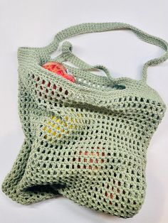 a crocheted green bag with an apple in the middle and two pieces of fruit inside