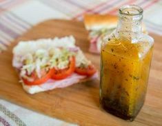 a bottle filled with food sitting on top of a cutting board next to a sandwich