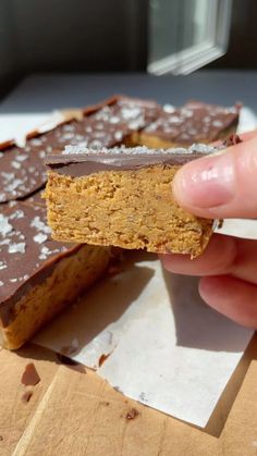 a person is holding a piece of chocolate and peanut butter bars in front of them