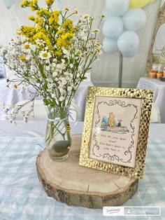 a vase filled with flowers sitting on top of a wooden table next to a sign