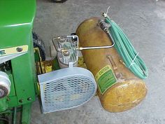 an old green machine sitting on the ground next to a wire fence and other equipment