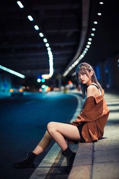 a woman sitting on the side of a road at night