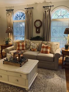 a living room with two couches and a coffee table in front of three windows