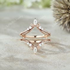 a rose gold ring with two diamonds on it and a pine cone in the background