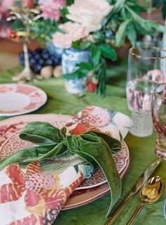 a table set with plates, silverware and green napkins on top of it