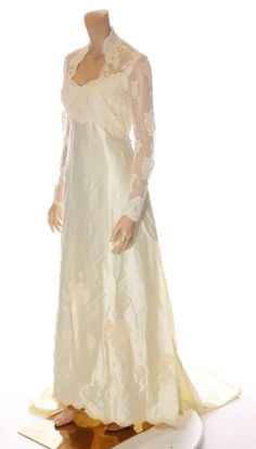 a mannequin dressed in a white dress with lace on the neck and sleeves