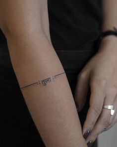 a woman's arm with an arrow tattoo on the left side of her arm