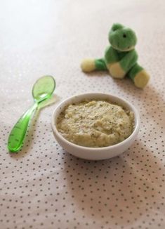 a small bowl of food next to a green spoon on a polka dot tablecloth