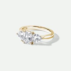 three stone ring in yellow gold with diamonds on the sides and an oval shaped diamond at the top