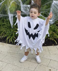 a young boy dressed up as a ghost for halloween with his hands in the air