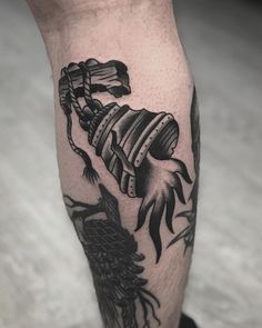 a man's leg with a tattoo on it and an arm that has a dragon holding a barrel