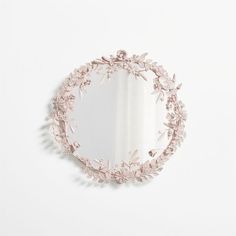 a mirror that is on the wall with flowers and leaves around it's edge