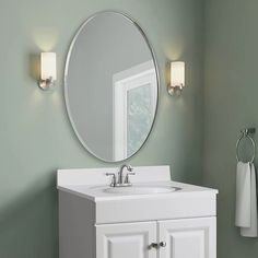 a bathroom vanity with a round mirror above it and two lights on either side of the sink