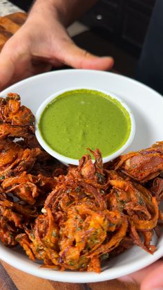 a white plate topped with fried food next to a green sauce