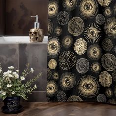 a black and gold shower curtain with an all seeing eye design on it next to a skull