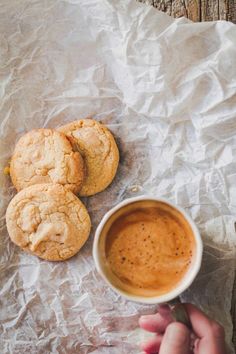 a person holding a cup of coffee and some cookies