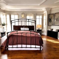 a bedroom with wood floors and white walls has a large bed in the center, along with two side tables