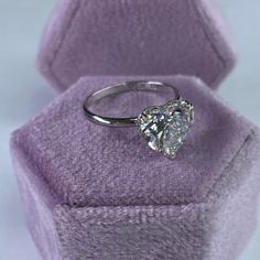 a diamond ring sitting on top of a purple velvet box