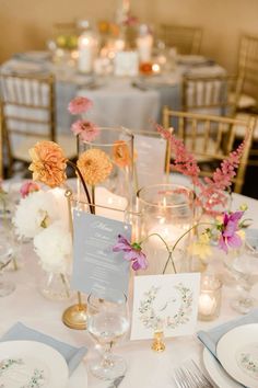 the table is set with flowers, candles and place cards for guests to sit at