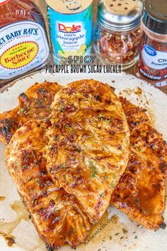 three pieces of pineapple brown sugar chicken on top of a white plate next to cans of sauce