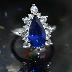 a blue and white diamond ring sitting on top of a table