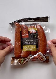 two hands holding a packaged hot dog