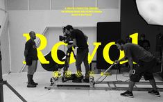 three men are filming in a studio with the words rcv1 on it and yellow letters