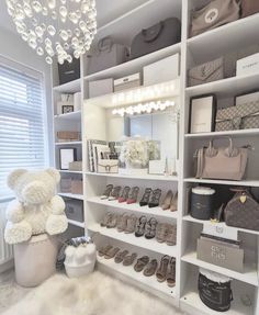 a white teddy bear sitting on top of a shelf next to shoes and purses