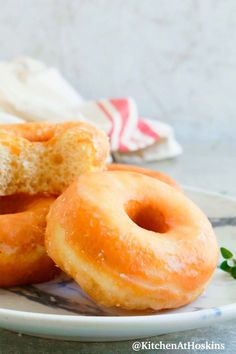 two glazed donuts on a plate with sprinkles and parsley in the background