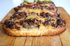 two pizzas with cheese and meat toppings sitting on a cutting board