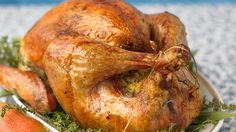 a turkey sitting on top of a white plate next to pears and oranges