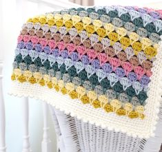 a crocheted blanket sitting on top of a white chair