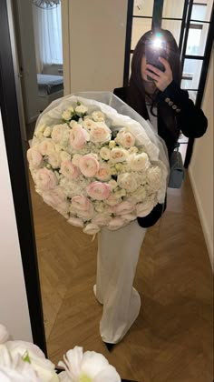 a woman taking a selfie while holding a bouquet of flowers