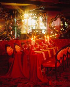 a dining room with red table cloths and candles on the tables in front of mirrors