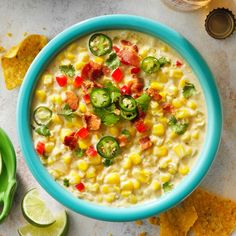 a bowl filled with corn and vegetables next to tortilla chips