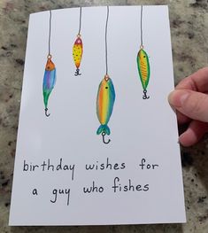 a hand holding up a birthday card with three fish on it and the words, birthday wishes for a guy who fishes