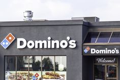 a domino's pizza shop front with the door open and sign above it that says domino's