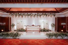 a wedding stage decorated with flowers and greenery for an event or reception in red carpeted room