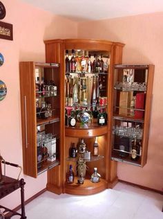 a corner liquor cabinet with lots of bottles in it